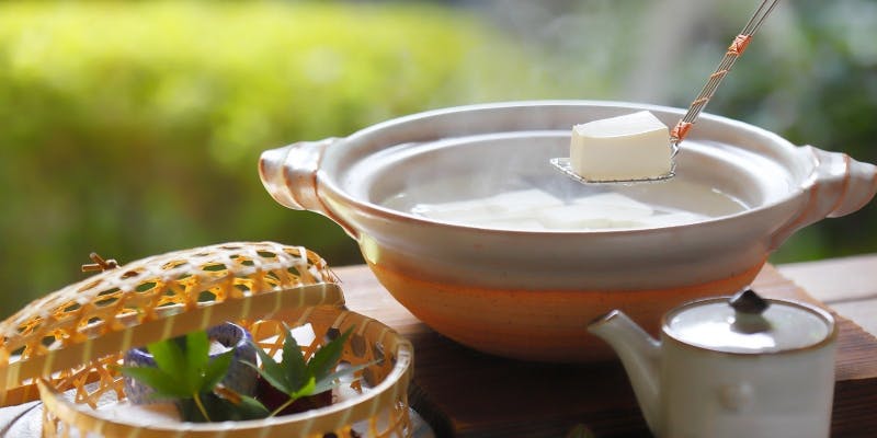 鍋から湯気が立つ湯豆腐と竹籠