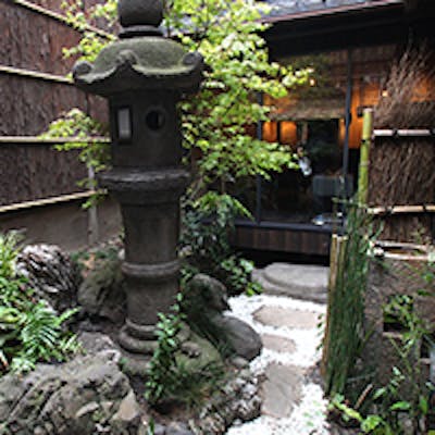 町屋造りの空間で、石灯籠がある和風庭園を眺めながら食事を楽しめる