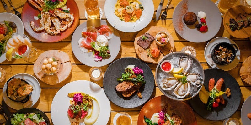 トウキョウ ウイスキー ライブラリーの肉料理やパスタなどがテーブルの上に置かれている様子