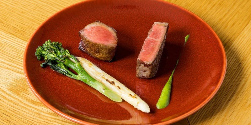 赤いお皿に盛られたステーキと野菜