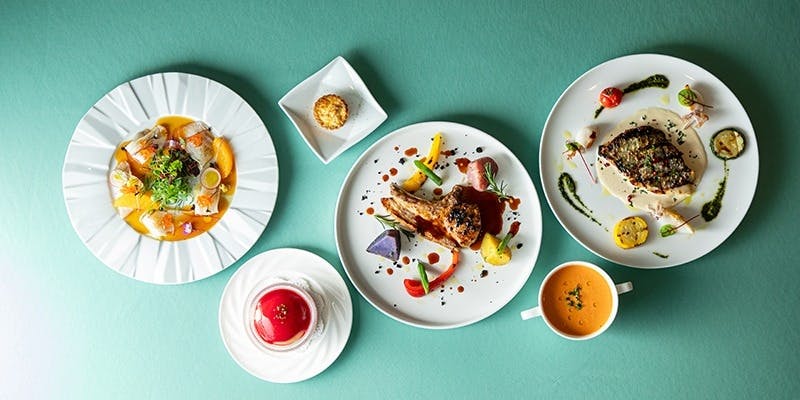 肉料理と魚料理、スープ、デザートなど6品が淡いブルーのテーブルに並んでいる