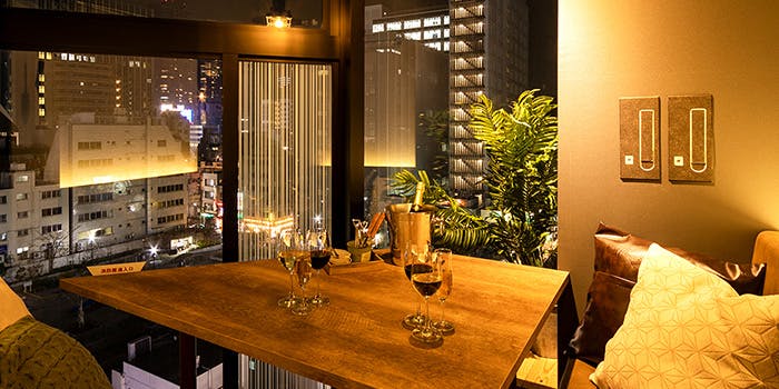 都会の夜景を眺められるテーブル席と赤ワインの入ったワイングラス