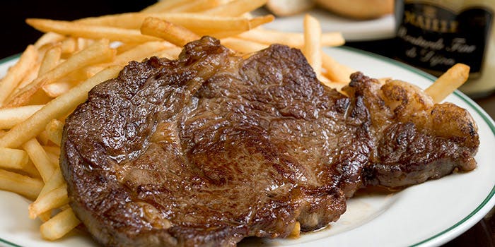 白い皿に盛りつけられた牛赤身肉のステーキとフライドポテト
