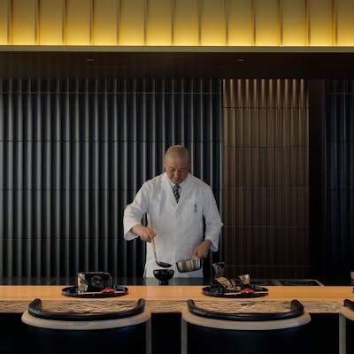 一枚板のカウンターや天井の和傘を模した照明が印象的な、シックで落ち着きのある空間