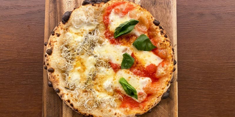木の皿にのったしらすチーズとマルゲリータのハーフピザ
