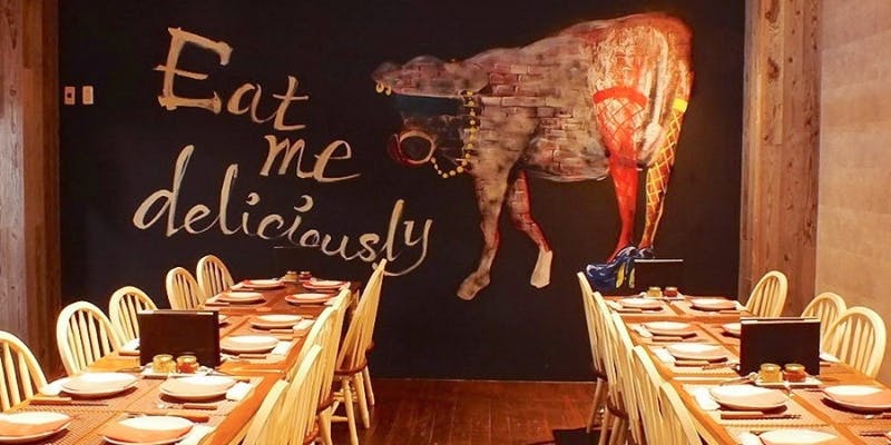 黒い壁に牛の絵が描かれたレストランの店内