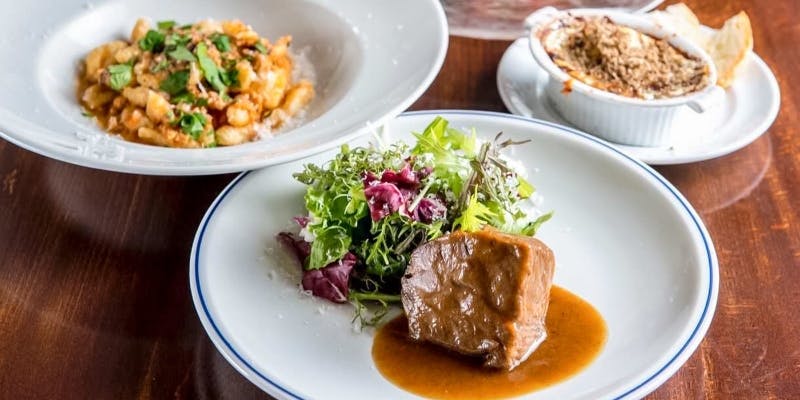 白い器に盛られたお肉料理とパスタ