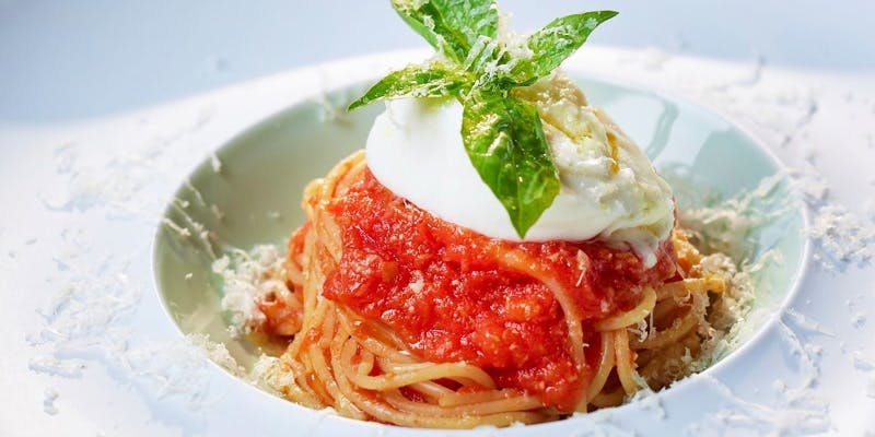 白い器に盛られたチーズののったトマトパスタ