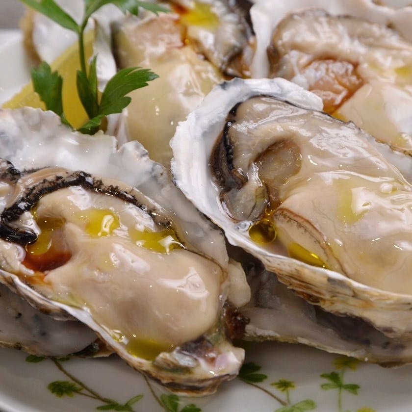 白いお皿に盛り付けれた産地直送の生牡蠣。少量のオリーブオイルが掛けられている