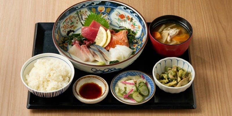 お盆にのった刺身盛り合わせとご飯と味噌汁と小鉢