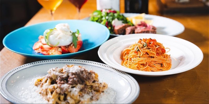 パスタや平打ち麺とステーキなどが並んだテーブル