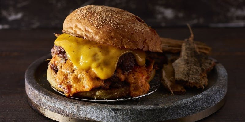 黒い器にのったチーズの入ったハンバーガー