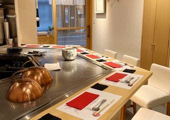 鉄板を囲むカウンターで、香ばしい音や香り、食材の食感の変化を堪能。木の温もりに包まれ、五感で味わう贅沢な鉄板焼きを。