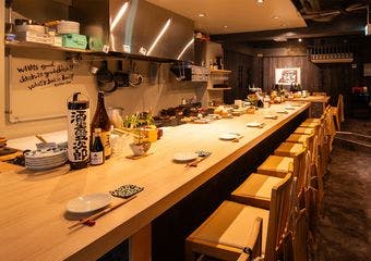 九州と岩手の郷土の味を丁寧に仕上げ、地酒やワインとともに。木のカウンターが迎える落ち着いた隠れ家です。